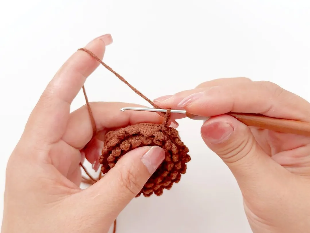 Hands working a round crochet piece with a crochet hook
